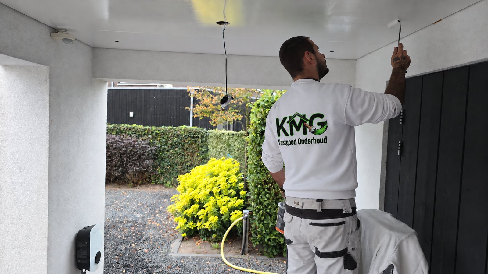 Schilder van KMG Vastgoedonderhoud schildert een plafond van een overkapping
